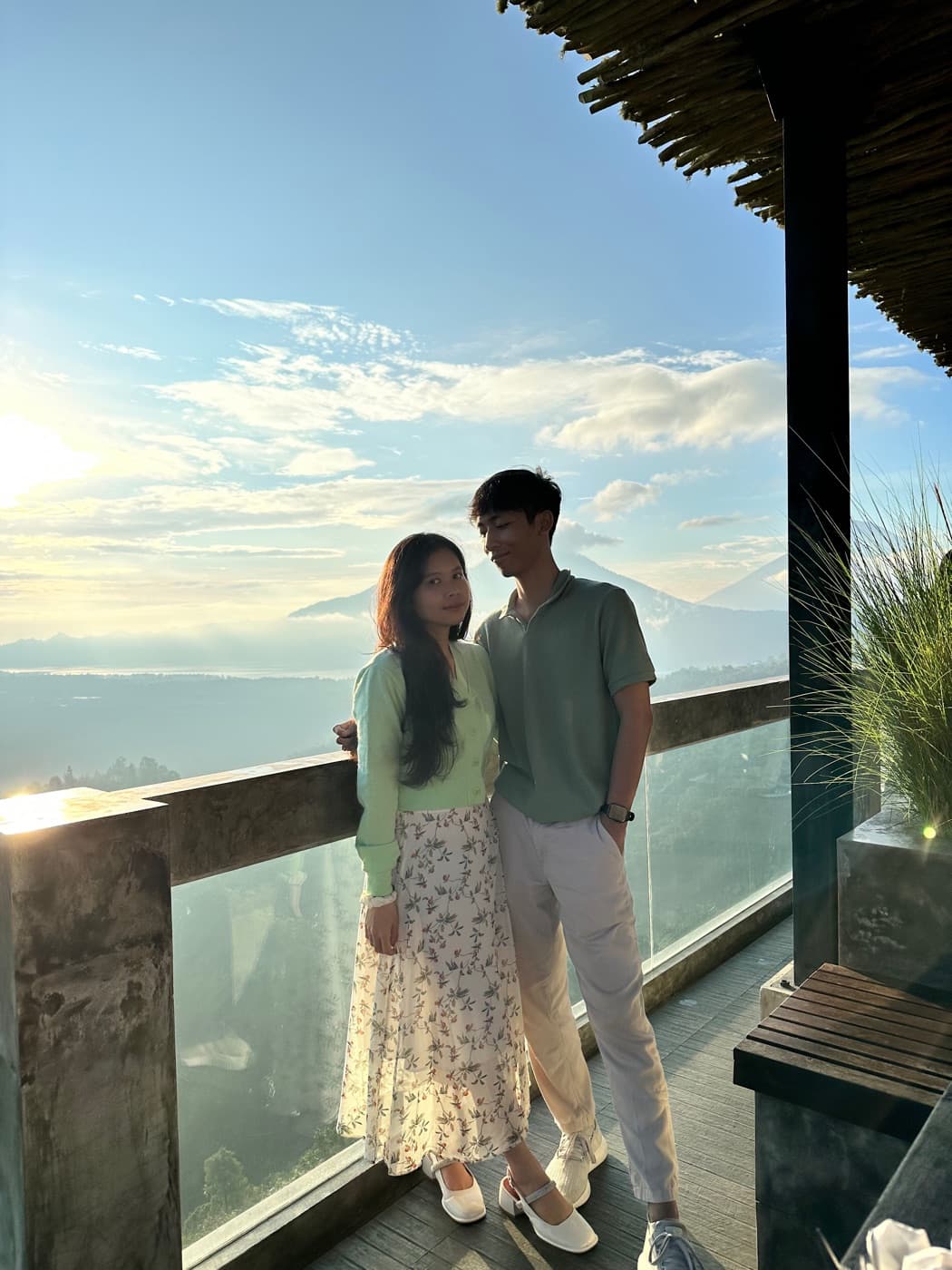 Ima and Sadu at sunrise on a glass-railed balcony above the clouds