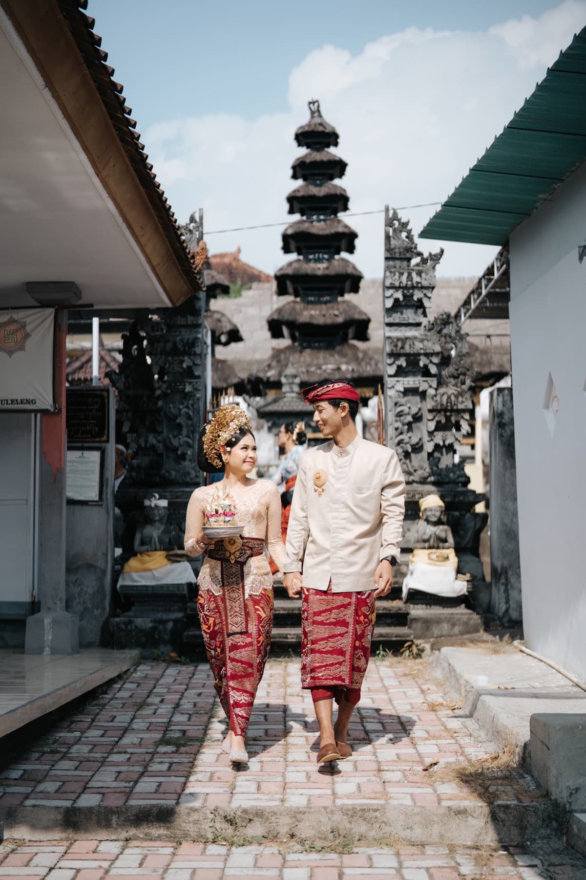 Ima and Sadu in Balinese wedding clothes, walking hand in hand out of a temple